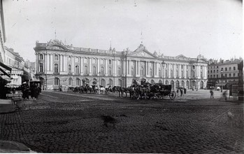 Toulouse (Haute-Garonne), hôtel de ville appelé Capitole. Référence : Place du Capitole. Fin 19e siècle. Vue d'ensemble de la place prise depuis l'angle nord-ouest. Au milieu plusieurs voitures à cheval, au fonds la façade de l'hôtel de ville.  Archives municipales de Toulouse (reproduction), Domaine public.